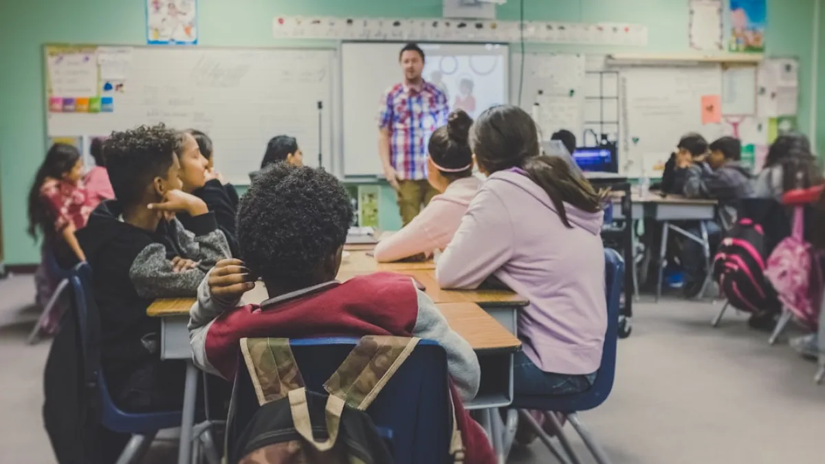 students in classroom with teacher presenting