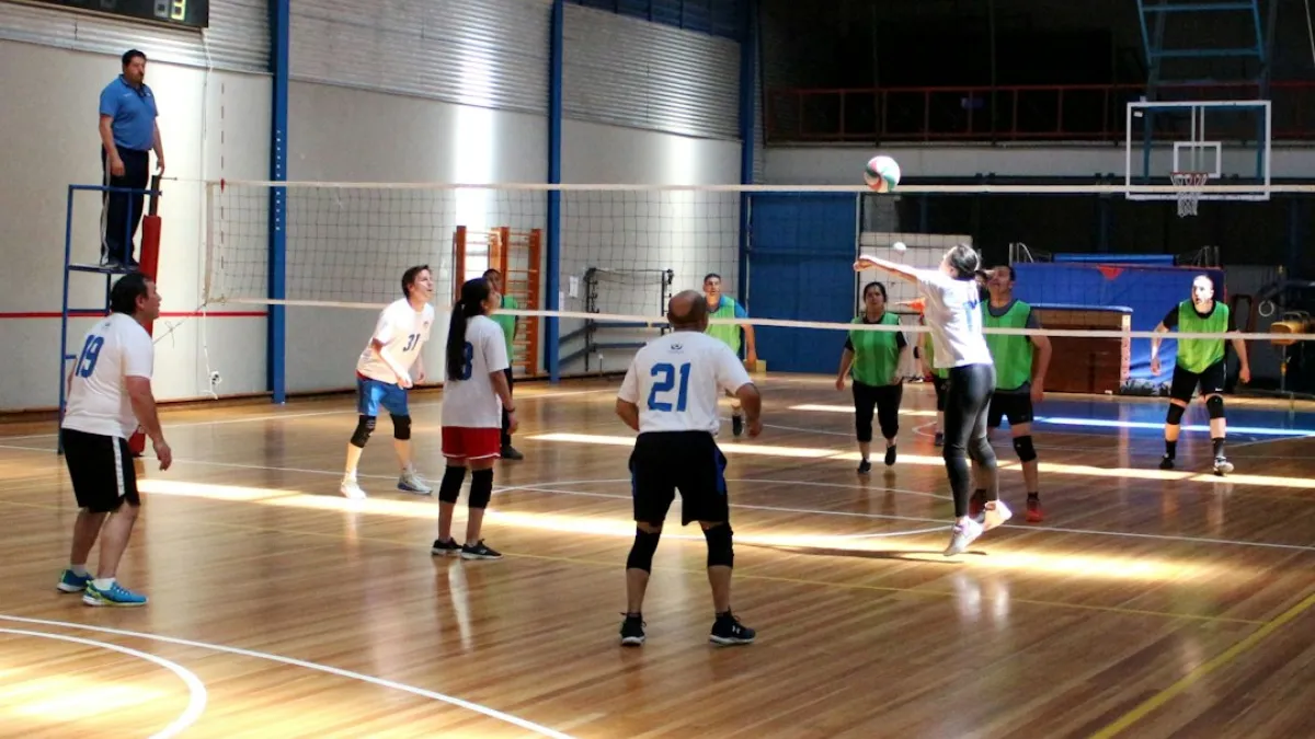 A group of people playing a volleyball match in an indoor sports hall