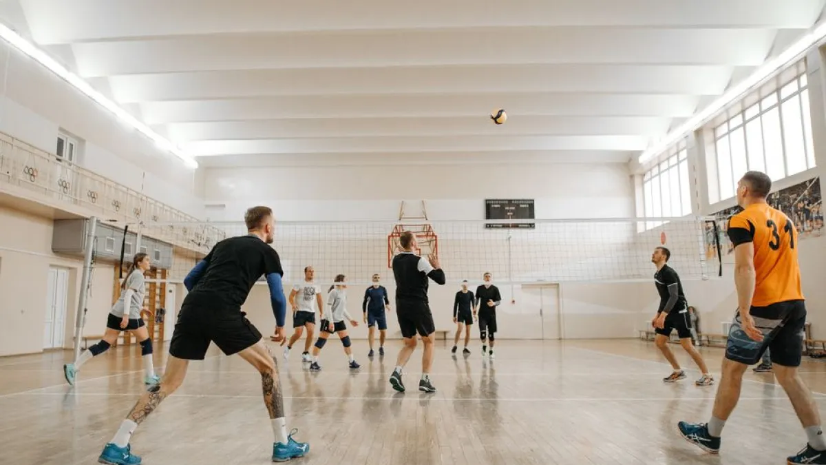 Indoor volleyball match featuring mixed-gender teams actively playing and competing.
