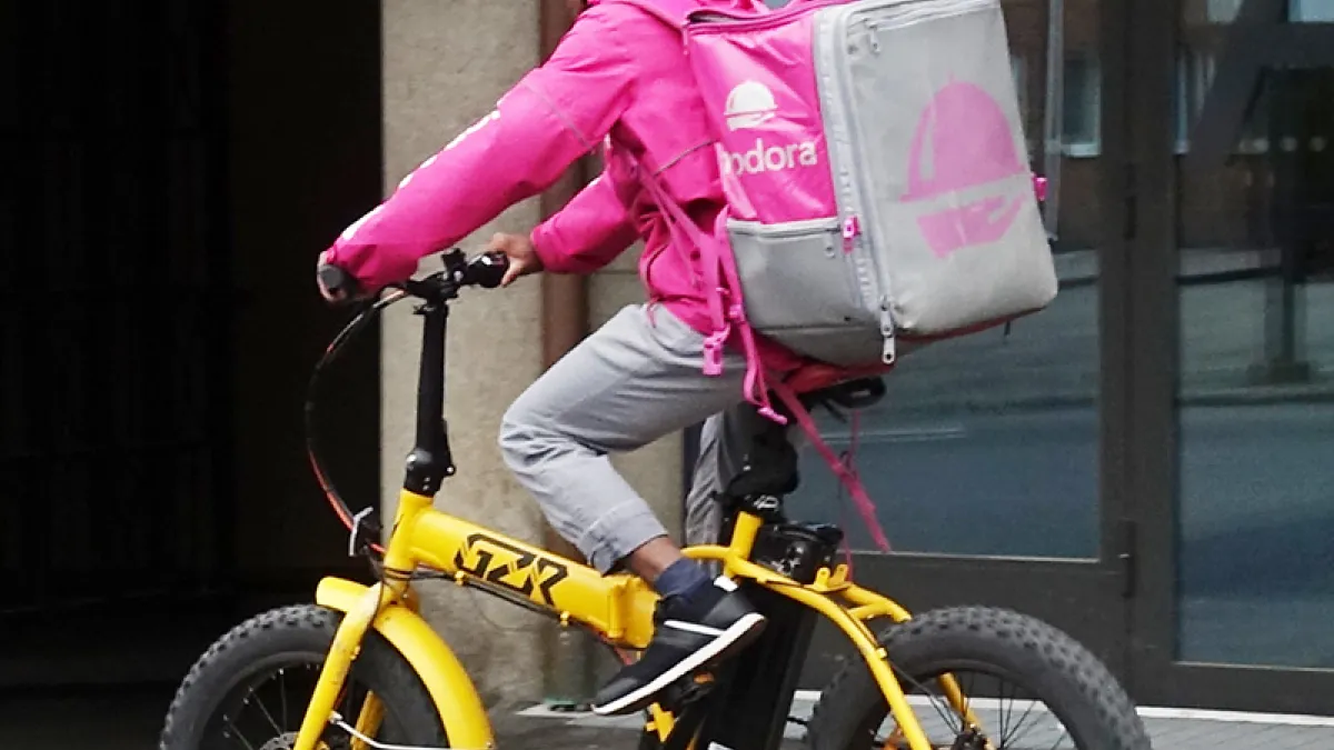 Foodora messenger bicycling on the street Satamakatu in Tampere, Finland.