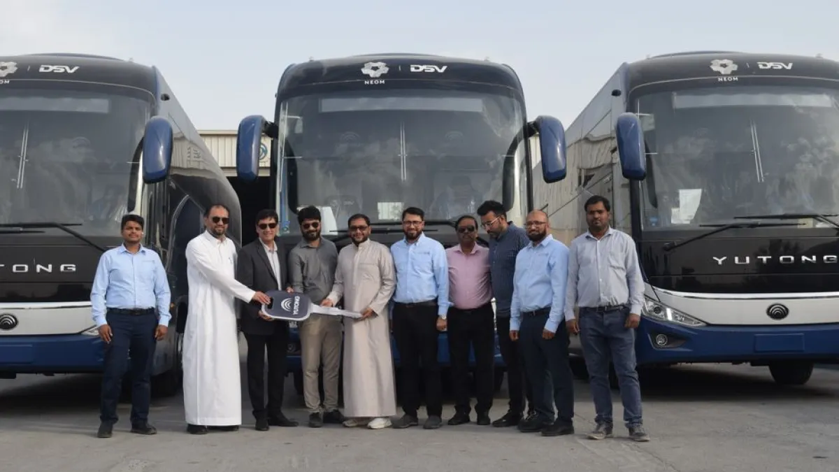 Group of businessmen posing in front of new Yutong buses for a handover ceremony.