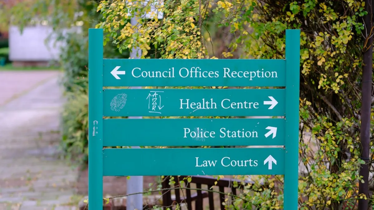 A green directional sign pointing to council offices, health centre, police station, and law courts