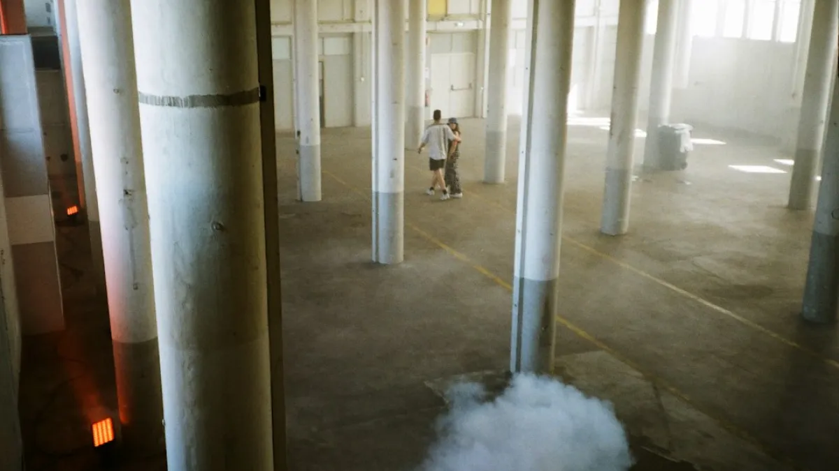 Two people walk through a large, empty industrial space