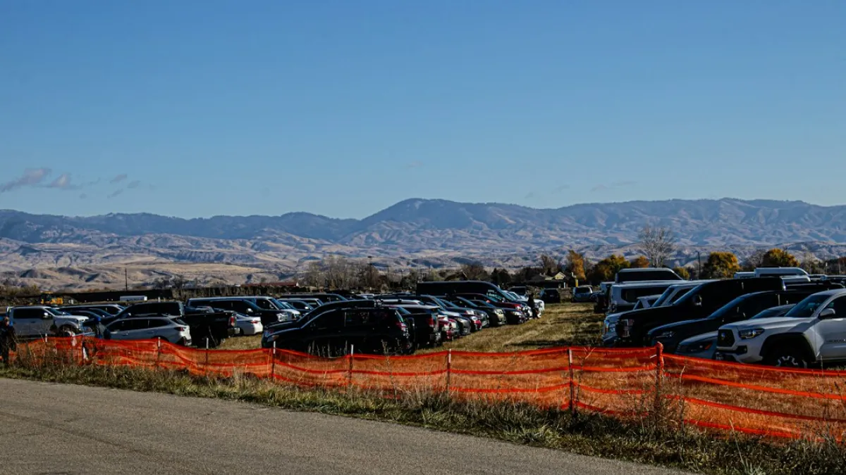 A parking lot filled with cars next to a fence