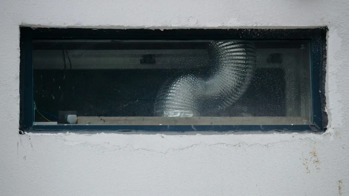 A flexible ventilation duct visible through a small rectangular window