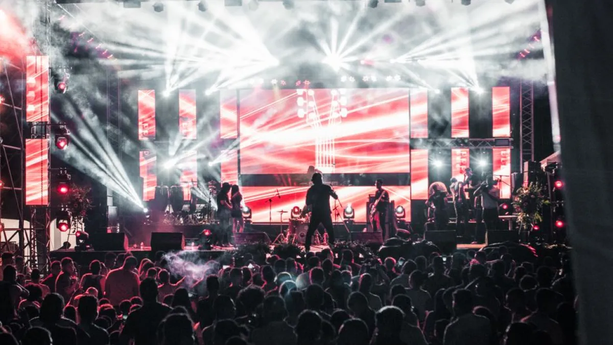 Energetic live music concert featuring performers on a vibrant stage, captivating a large audience.