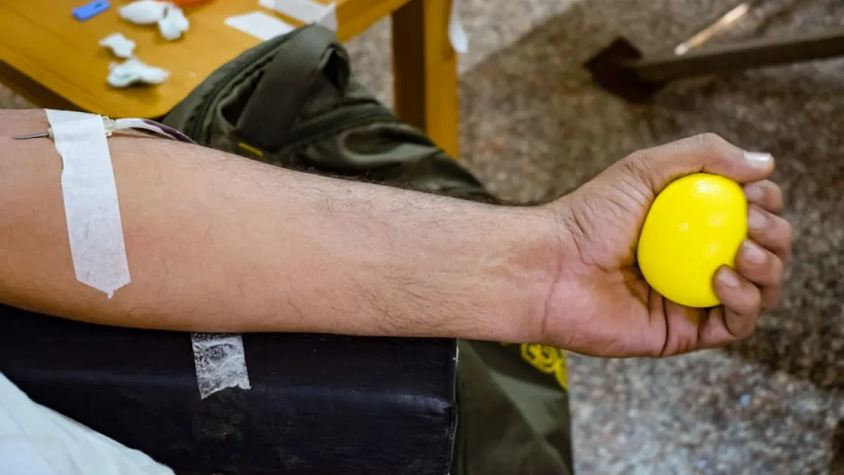 Detailed shot of a person's arm donating blood, squeezing a yellow stress ball.