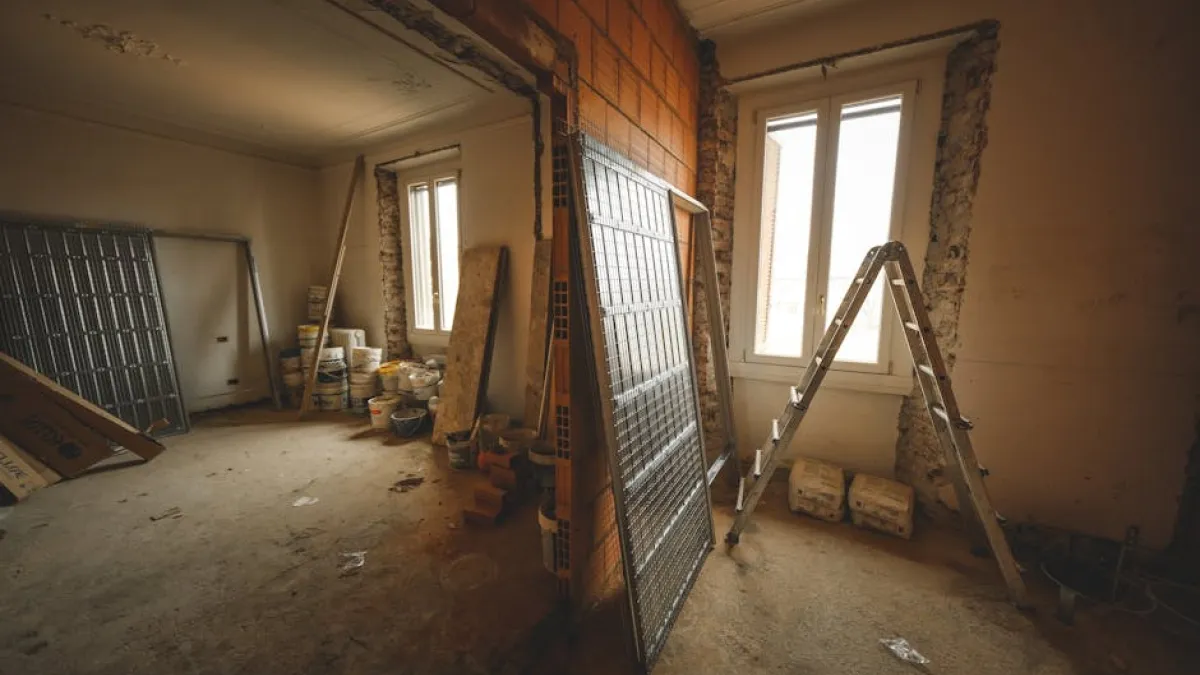 Interior view of a room under renovation with construction materials and a ladder.