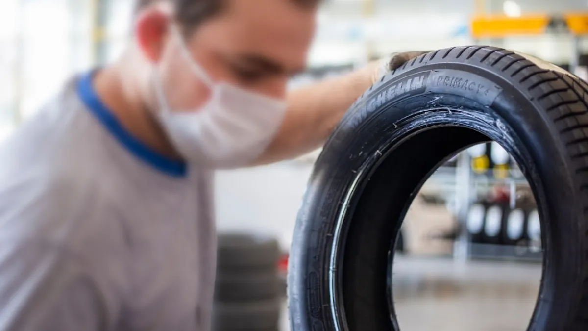 man in white shirt holding black tire