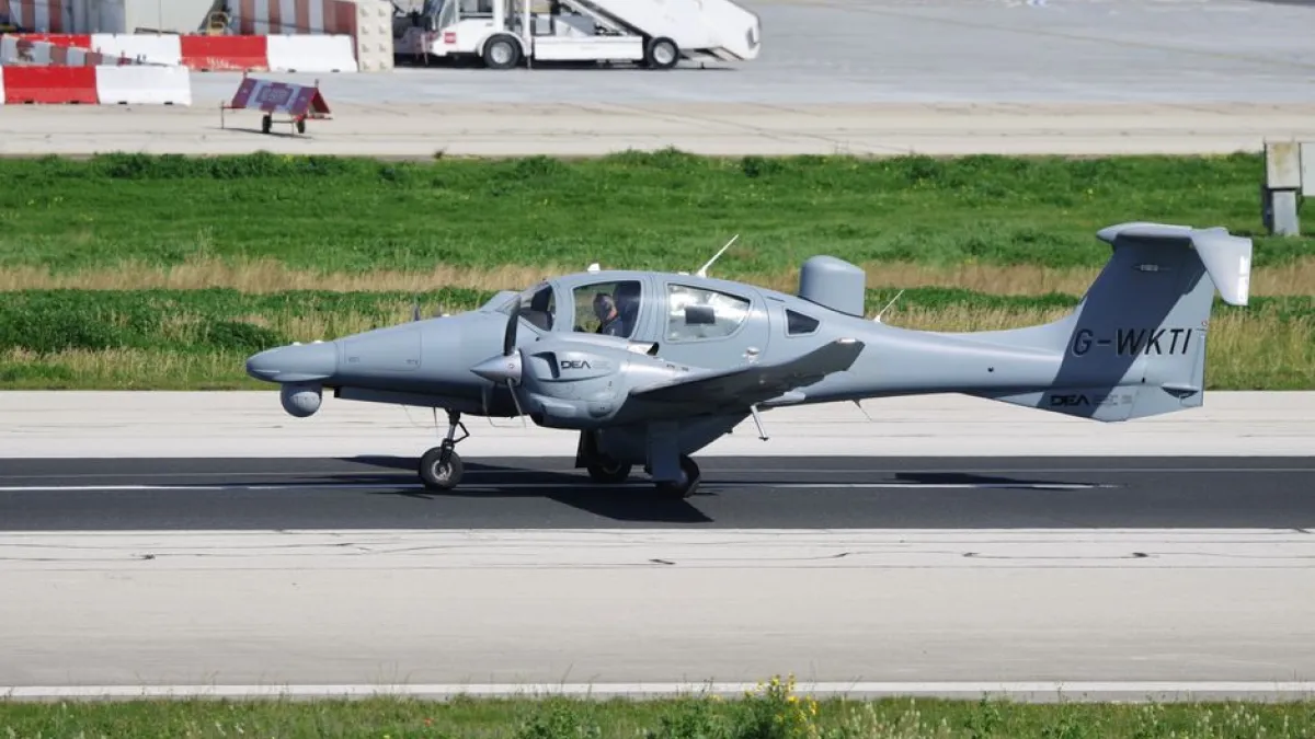 Diamond DA42 aircraft taxiing on airport runway under clear skies.