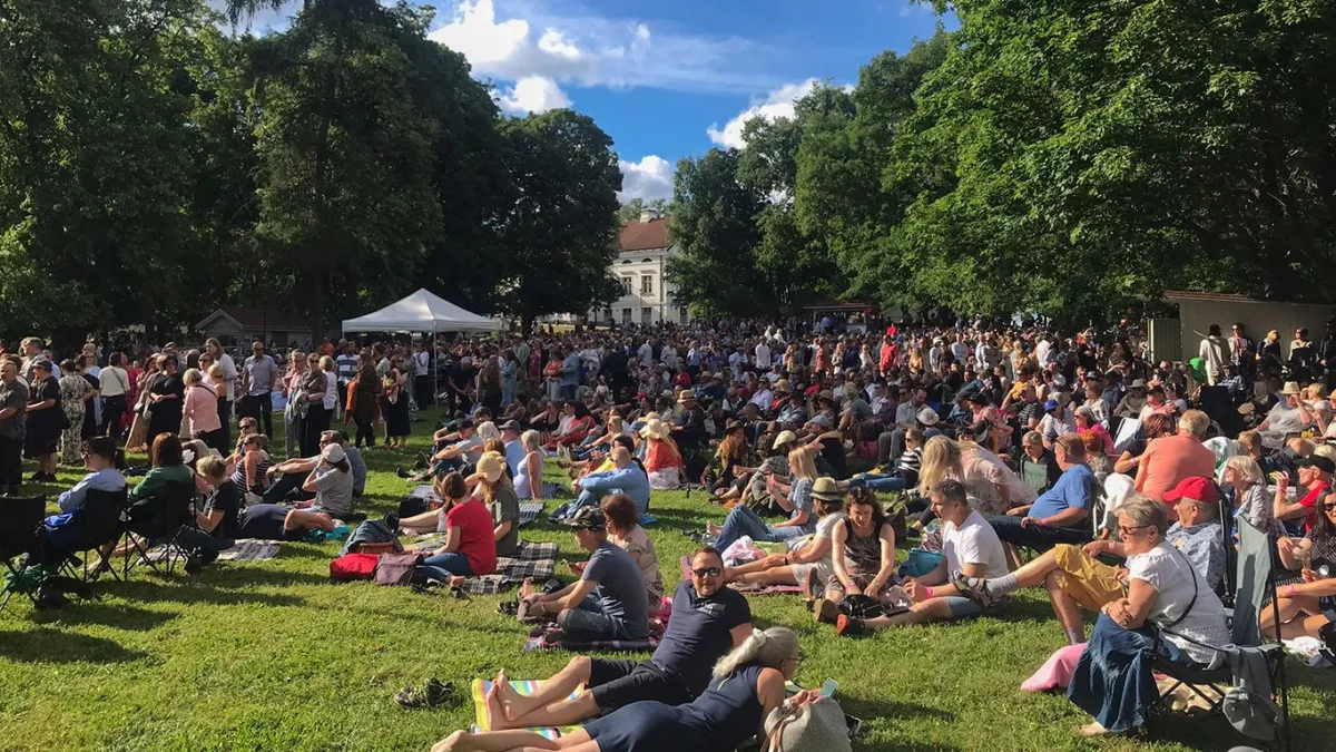 Ihmisiä puistossa kuuntelemassa musiikkia
