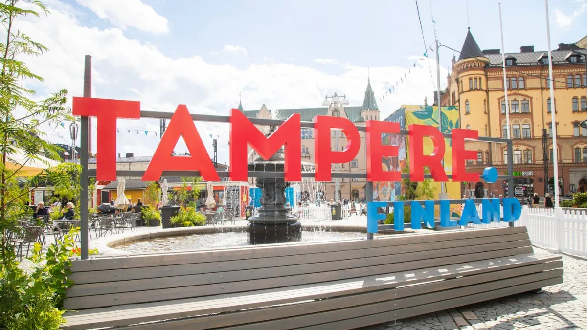 Tampereen keskustorin suihkulähde, jonka edessä Tampere.Finland-tekstillä varustettu kuvausteline. Taustalla jugend-tyylisiä rakennuksia.