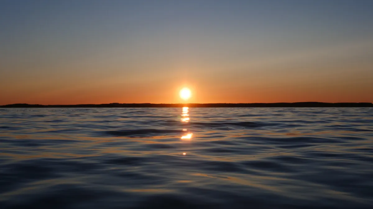 Peaceful sunset over rippled water in Teisko, Pirkanmaa, Finland, capturing reflections and tranquility.