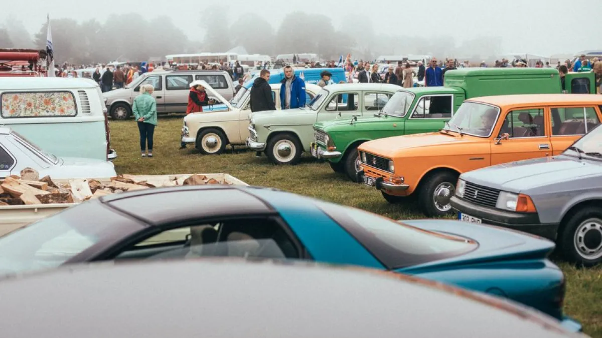 A vibrant gathering showcasing classic cars with enthusiastic crowds on a foggy day.